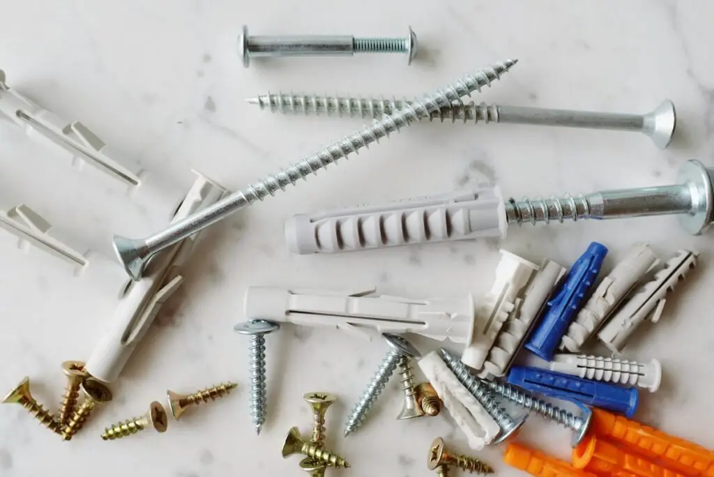 Various types of wall anchors and screws needed to find the right drill bit for a 3/8 anchor.