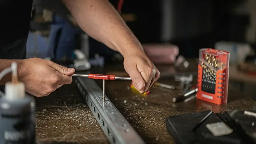 Applying cutting fluid while using a 10-24 tap to create clean threads in metal.